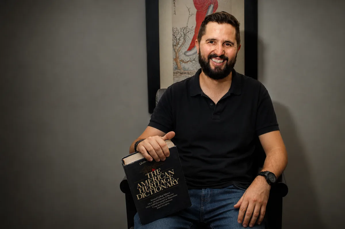 Lucas Witty, fundador e professor da Inglês Witty, com dicionário de inglês